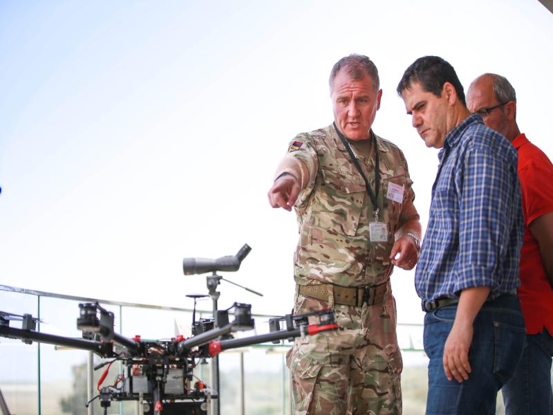 Major James Fawcett MBE points at a mozzycopter